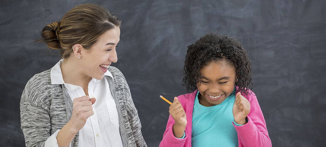 Schülerin lacht mit Lehrerin