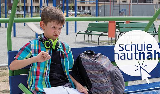 grantiger Schüler sitzt auf einer Parkbank