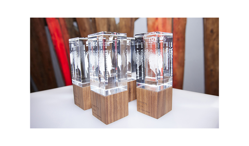 Mehrere gläserne Trophäen mit Holzsockeln auf einem Tisch beim TÜV AUSTRIA Wissenschaftspreis.
