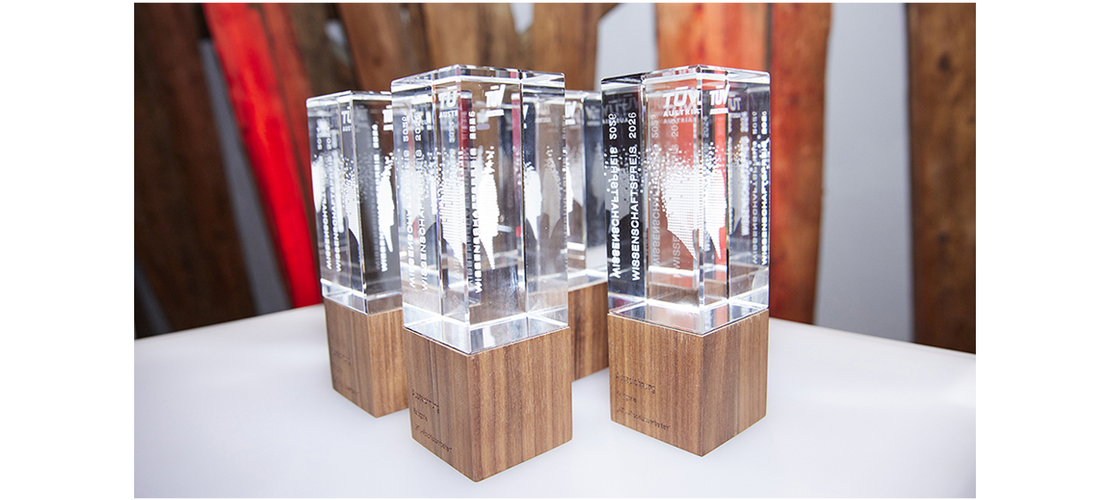 Mehrere gläserne Trophäen mit Holzsockeln auf einem Tisch beim TÜV AUSTRIA Wissenschaftspreis.