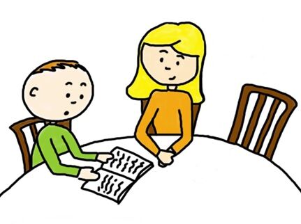 Ein Junge und ein Mädchen sitzen an einem Tisch. Der Junge liest ein Buch.
