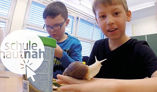 Schüler in der Klasse mit einer Achatschnecke auf der Hand