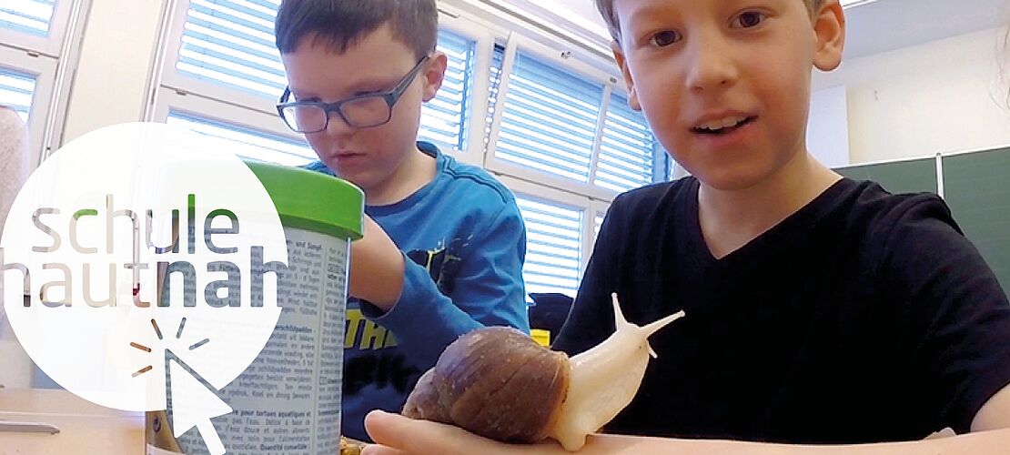 Schüler in der Klasse mit einer Achatschnecke auf der Hand