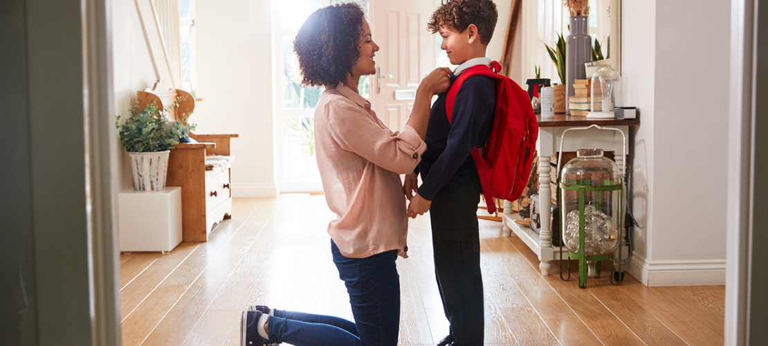 Mutter verabschiedet zuhause ihren Sohn in den ersten Schultag