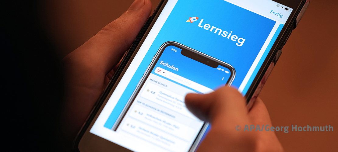 Hände halten Smartphone mit geöffneter App namens Lernsieg