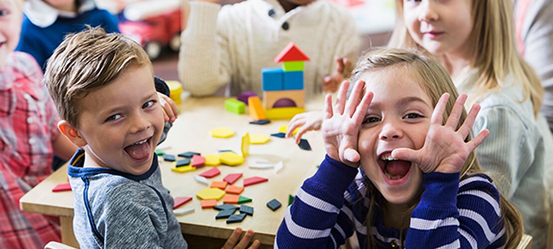 fröhliche Kindergartenkinder um einen Tisch