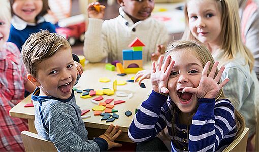 fröhliche Kindergartenkinder um einen Tisch