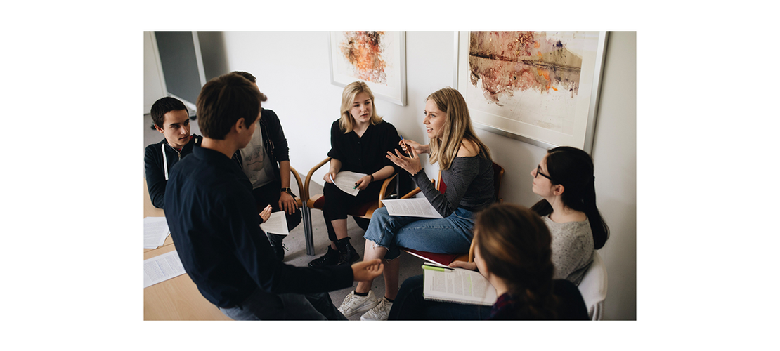 eine Gruppe von Schülerinnen und Schülern, die zusammensitzen und sich unterhalten