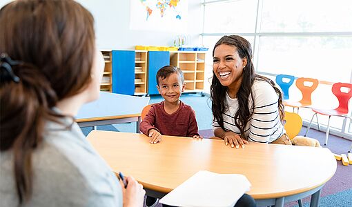 Eine Lehrerin redet mit einem Schüler und dessen Mutter