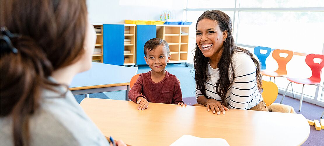 Eine Lehrerin redet mit einem Schüler und dessen Mutter