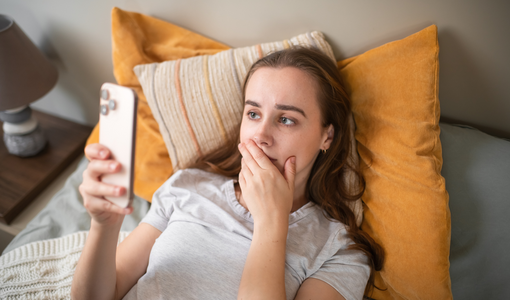 Besorgte junge Frau mit Smartphone zu Hause