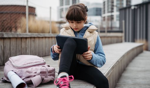 Halfpoint via Gettyimages Kind sitzt vor Schule und surft im Internet