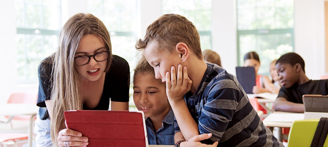 Lehrerin arbeitet in einer Schulklasse mit einem Tablet