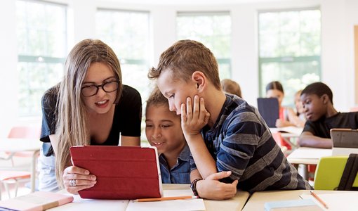 Lehrerin arbeitet in einer Schulklasse mit einem Tablet