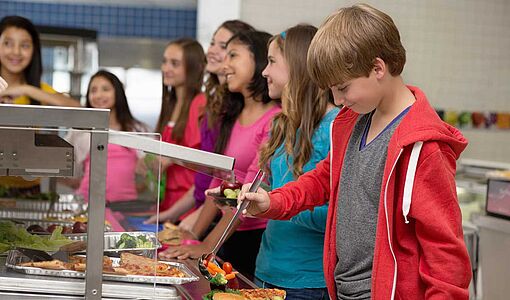 Schüler stellen sich beim Mittagessen in der Schulküche an