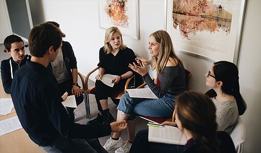 eine Gruppe von Schülerinnen und Schülern, die zusammensitzen und sich unterhalten