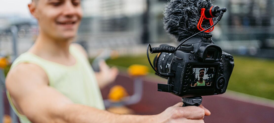 Junger muskulöser Mann, der Vlog in einem Outdoor-Fitnessstudio aufnimmt -