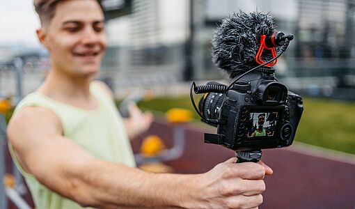 Junger muskulöser Mann, der Vlog in einem Outdoor-Fitnessstudio aufnimmt -