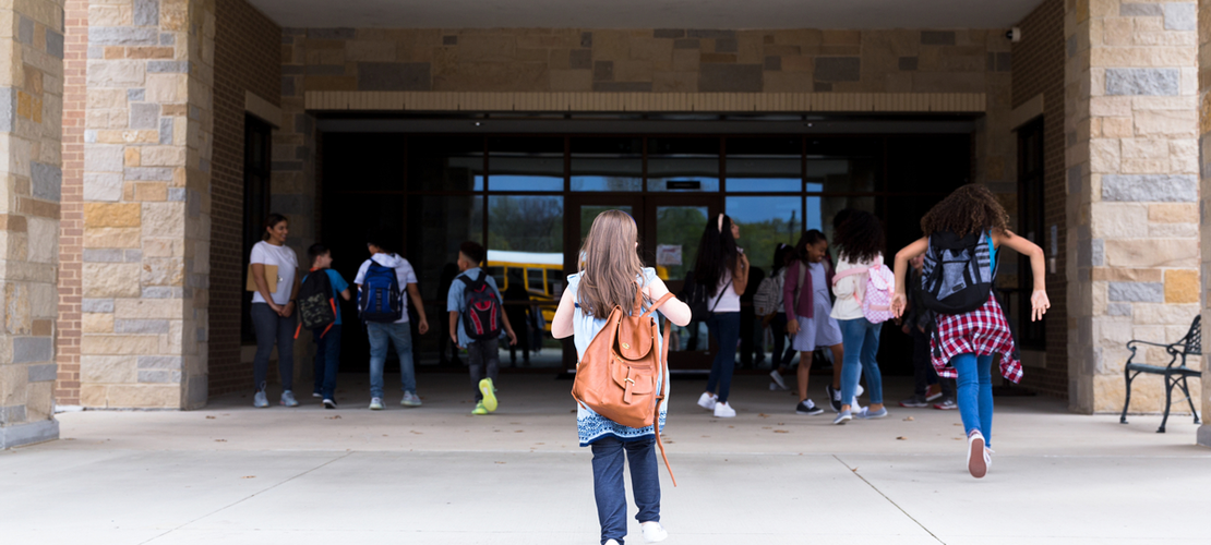 Schülerinnen und Schüler rennen ins Schulgebäude