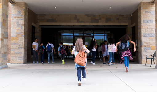 Schülerinnen und Schüler rennen ins Schulgebäude