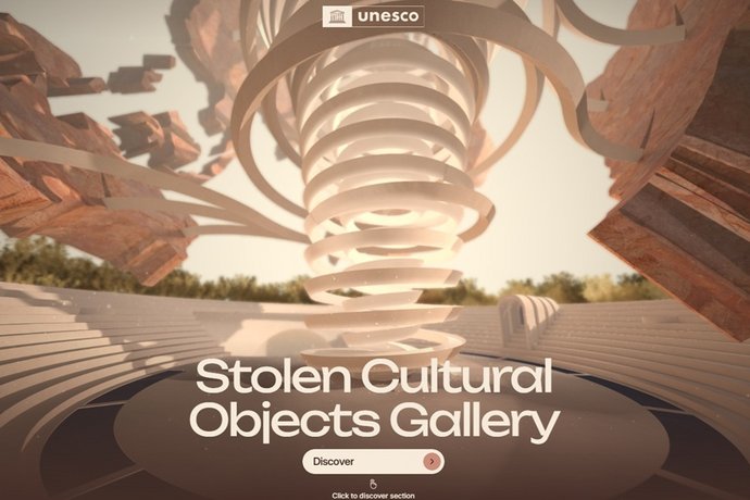 Ein rundes Amphitheater mit einer großen spiralförmigen Skulptur steht im Freien, umgeben von Bäumen.