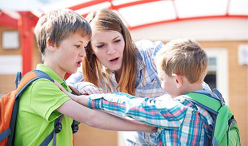 2 Schüler streiten sich und die Lehrerin geht dazwischen