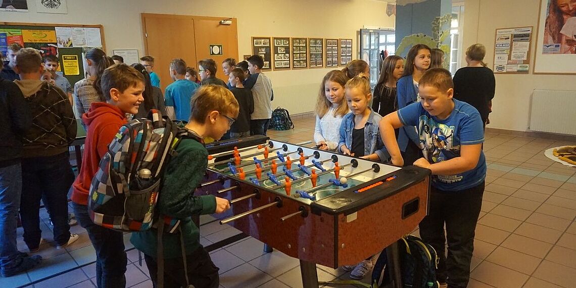 Schülerinnen und Schüler spielen gemeinsam am Wuzzler Fußball