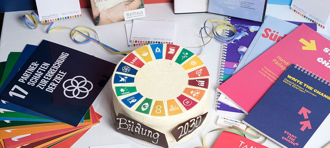Geburtstagstorte, Flyer und Bücher bzw. Bildungsmaterialien rund um die 17 Nachhaltigskeitsziele der Agenda 2030 der Vereinten Nationen