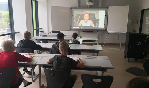 SchülerInnen im Klassenzimmer nehmen an einer Videokonferenz teil