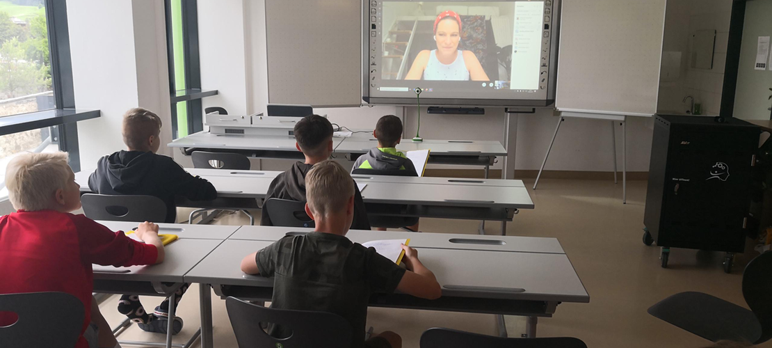 SchülerInnen im Klassenzimmer nehmen an einer Videokonferenz teil