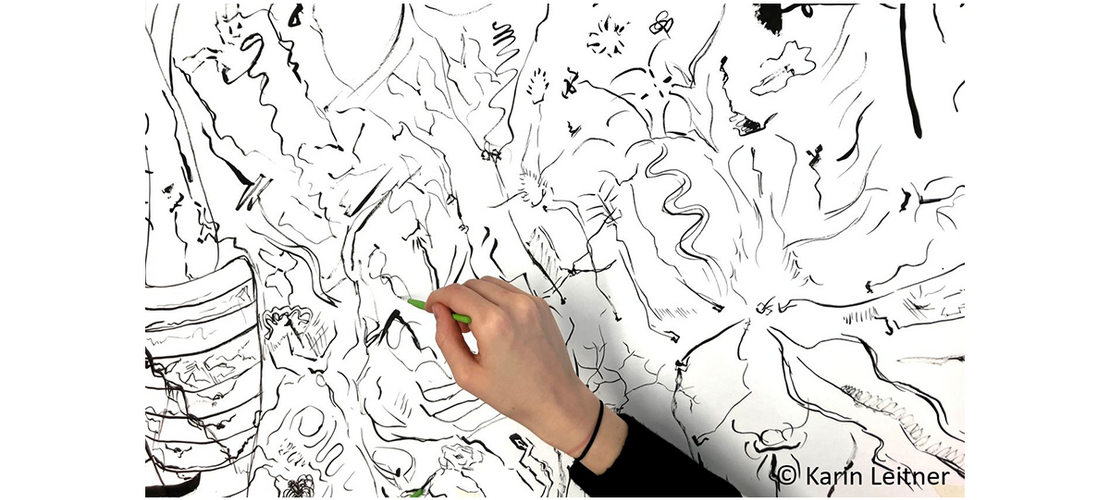 projekteuropa_2025-26_c-Karin-Leitner Hand zeichnet mit grünem Stift auf großem schwarz-weißem Linienbild.